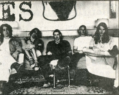 The Dragmules members line shoulder to shoulder on a couch.